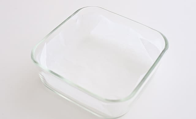 耐熱容器にオーブンシートを敷き込んでいる写真