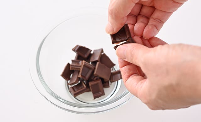 チョコレートを手で小さく割っている写真