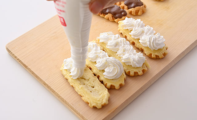 『チーズワッフル』にホイップクリームを絞っている写真