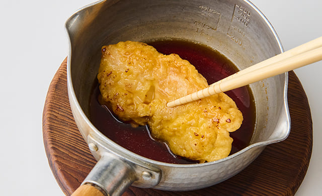 鶏肉を甘酢だれに絡めている写真
