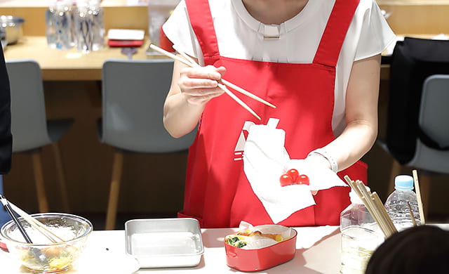 「冷凍唐揚げで黒酢の酢どり弁当」でミニトマトの水気を切る阪下千恵先生