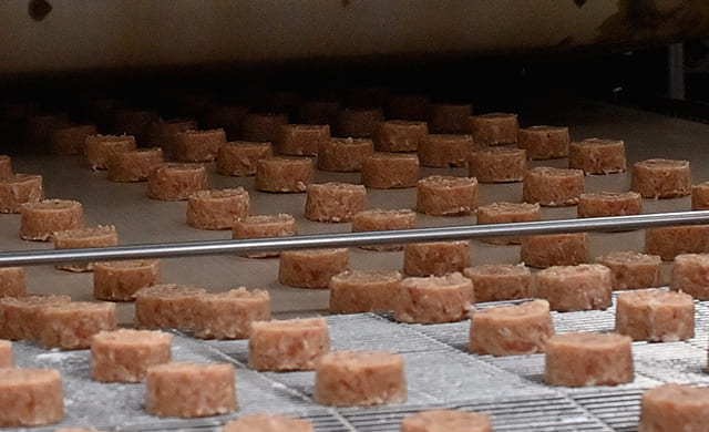 『ミニハンバーグ』がWベルトグリルに運ばれて焼かれる前の写真