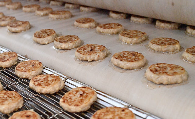 『ミニハンバーグ』がWベルトグリルに運ばれて焼かれた後の写真