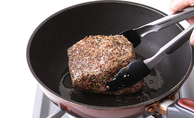 牛ももブロック肉に焼き色をつけている写真