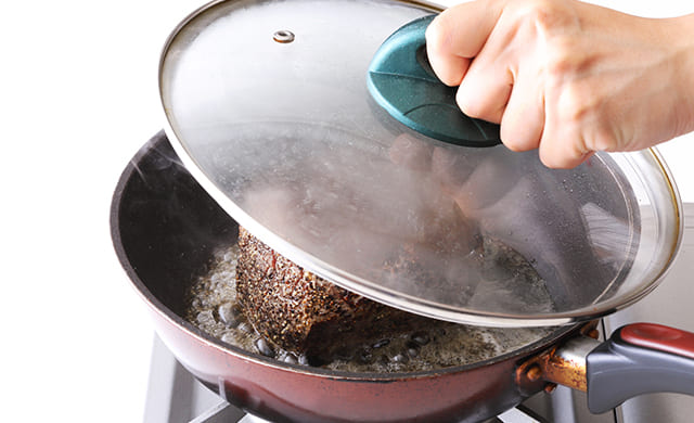 ふたをして肉を蒸し焼きにしている写真