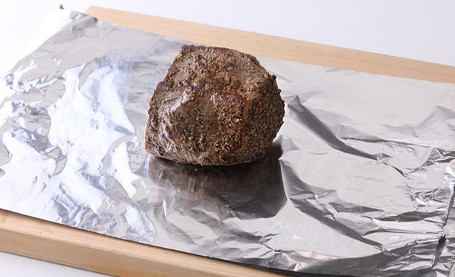 3枚重ねたアルミホイルに肉をのせた写真