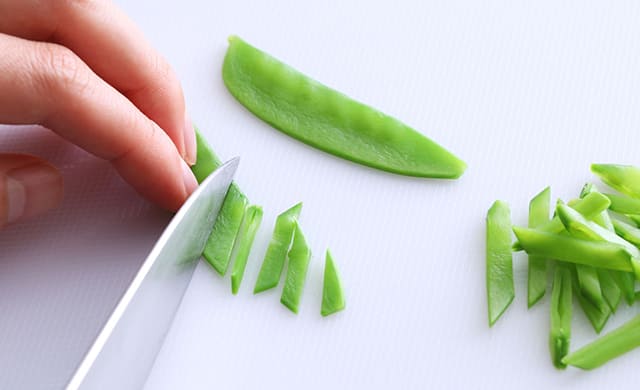 ゆでた絹さやを斜め千切りにしている写真