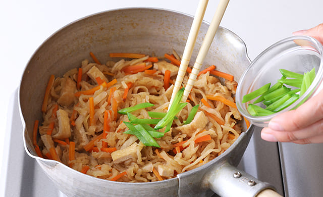 切り干し大根の煮物に絹さやを加えている写真