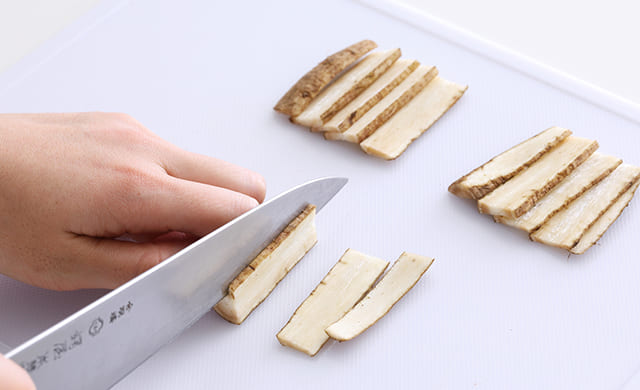 ぶつ切りのごぼうをスライスしている写真