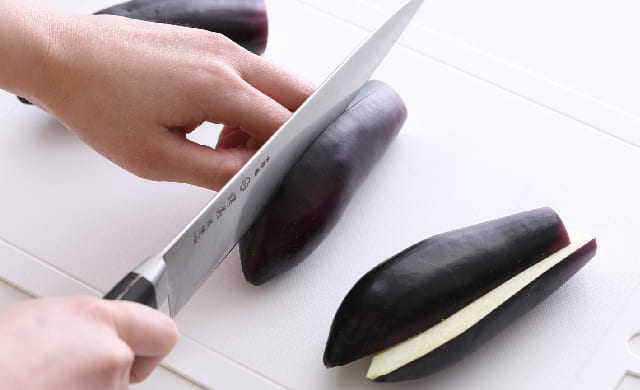 なすを縦半分に切っている写真