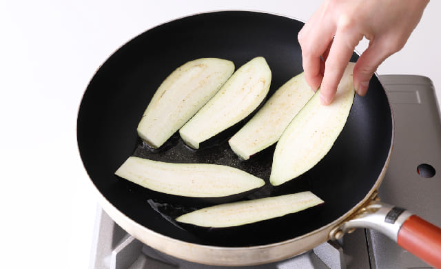 フライパンになすを皮目を下にして並べている写真